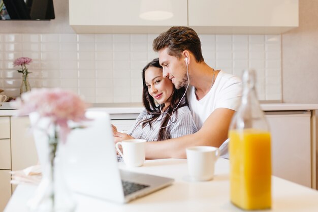 Coppia di innamorati ascoltando musica insieme durante la colazione nell'accogliente cucina