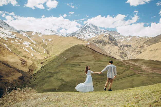 coppia di innamorati cammina sullo sfondo di alte montagne con ghiacciai al culmine