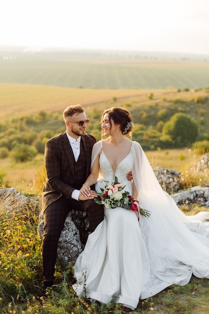 Coppia di innamorati matrimonio sposini fuori al tramonto in una bella giornata estiva