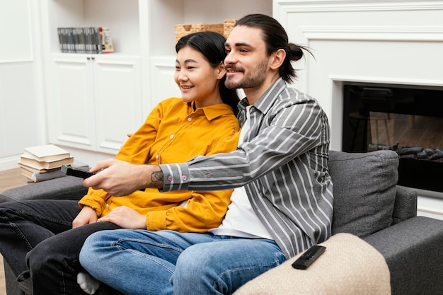 Coppia di lato seduto sul divano a guardare la tv