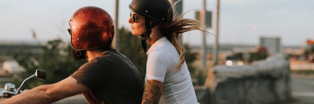 Coppia di motociclisti che guidano lungo la strada al tramonto