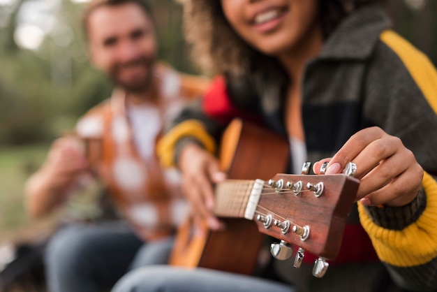 Coppia di smiley suonare la chitarra all'aperto durante il campeggio