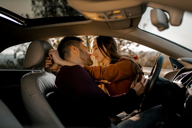 Coppia di tiro medio essendo romantica in macchina