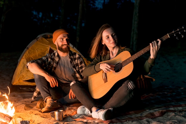 Coppia felice cantando e suonando la chitarra