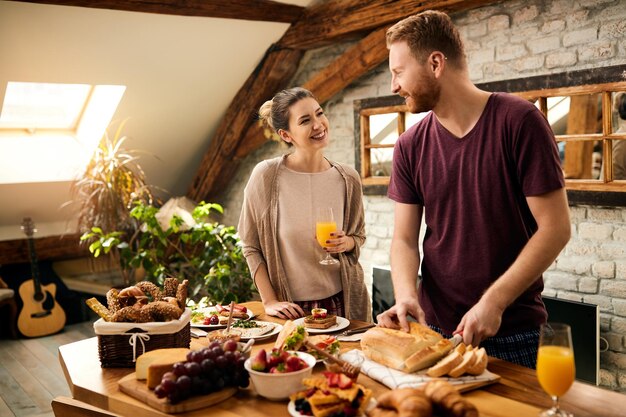 Coppia felice che comunica mentre prepara la colazione nella sala da pranzo