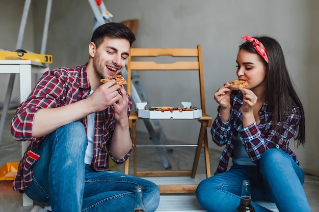 Coppia felice che fa le riparazioni a casa e ha un momento romantico per mangiare la pizza