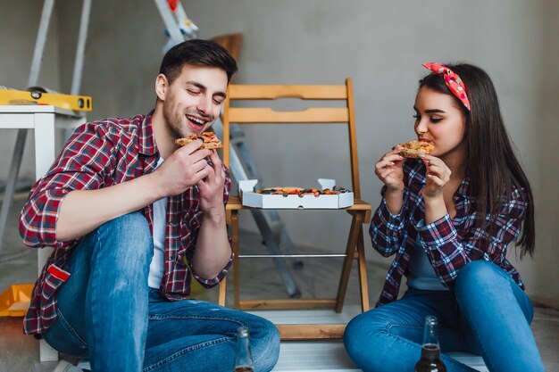 Coppia felice che fa le riparazioni a casa e ha un momento romantico per mangiare la pizza