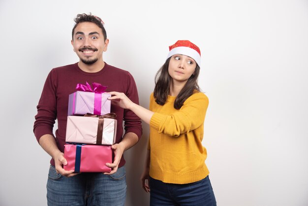 Coppia felice con regali di Natale su un muro bianco.