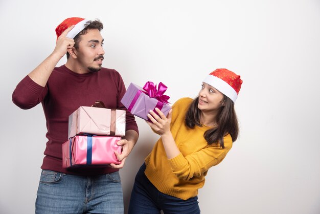 Coppia felice con regali di Natale su un muro bianco.