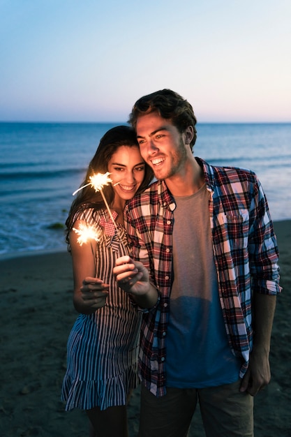 Coppia felice con sparkler in spiaggia