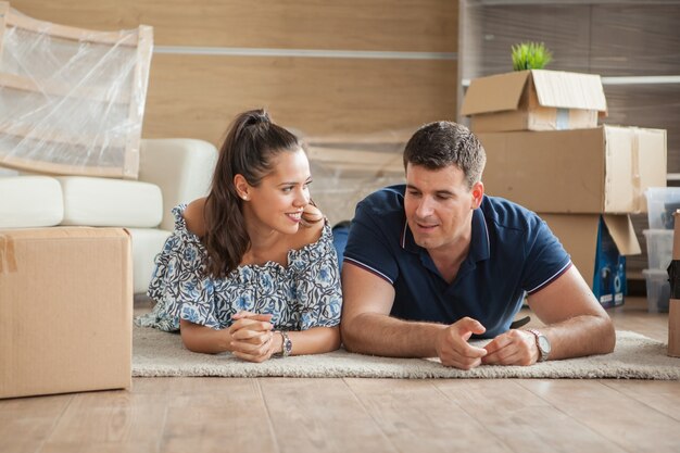 Coppia felice sdraiata sul pavimento della loro nuova casa. Mutuo e famiglia