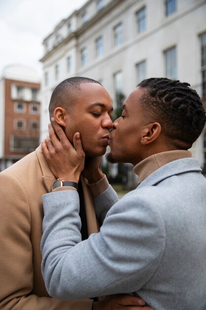Coppia gay che condivide un bacio all'aperto in città