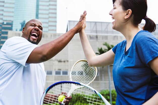 Coppia giocando a tennis in gruppo