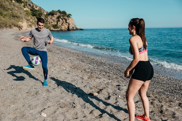 Coppia giocare a calcio in spiaggia