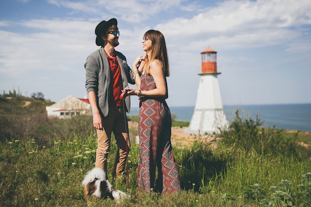 Coppia giovane hipster alla moda nell'amore che cammina con il cane in campagna