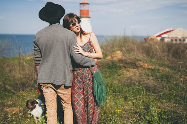 Coppia giovane hipster alla moda nell'amore che cammina con il cane in campagna