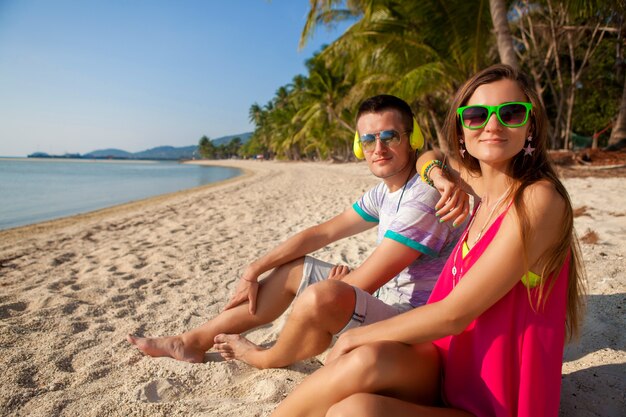 Coppia giovane hipster in amore, spiaggia tropicale, vacanze, stile alla moda estivo, occhiali da sole, cuffie