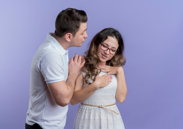 Coppia giovane uomo chiedendo il suo girlfrined perdono in piedi oltre il muro blu