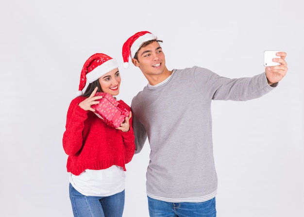 Coppia in cappelli di Natale prendendo selfie