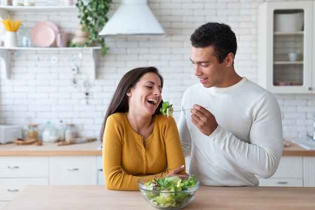 Coppia in cucina a mangiare insalata