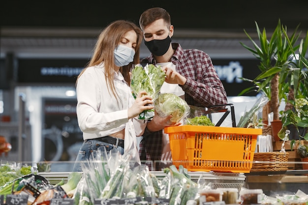 Coppia in maschera protettiva medica in un supermercato.