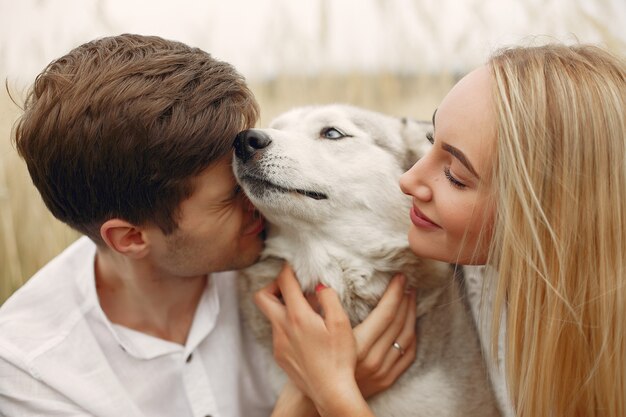 Coppia in un campo autunnale a giocare con un cane