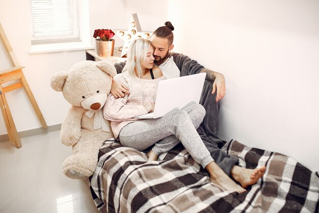 Coppia la seduta su un letto in una stanza e usi un computer portatile