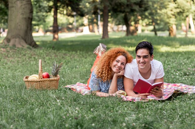 Coppia leggendo un libro insieme al parco