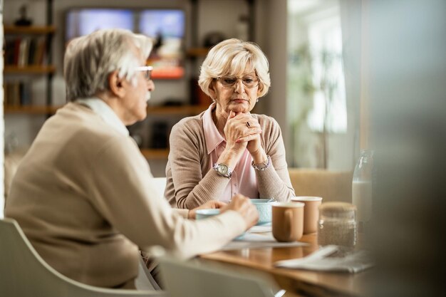 Coppia matura pensando a qualcosa durante la colazione a casa Focus è sulla donna pensierosa