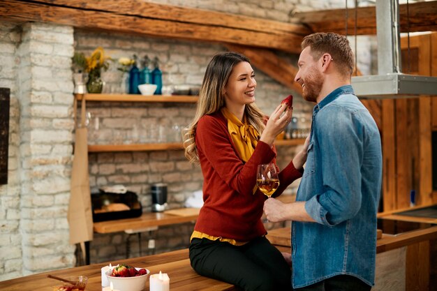 Coppia romantica che mangia fragole mentre beve vino a casa