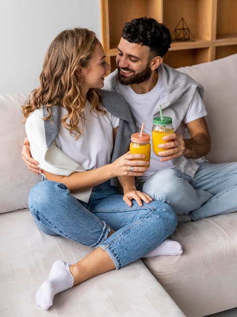 Coppia romantica con succo di frutta sul divano di casa