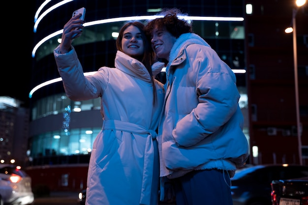Coppia romantica in città di notte prendendo selfie
