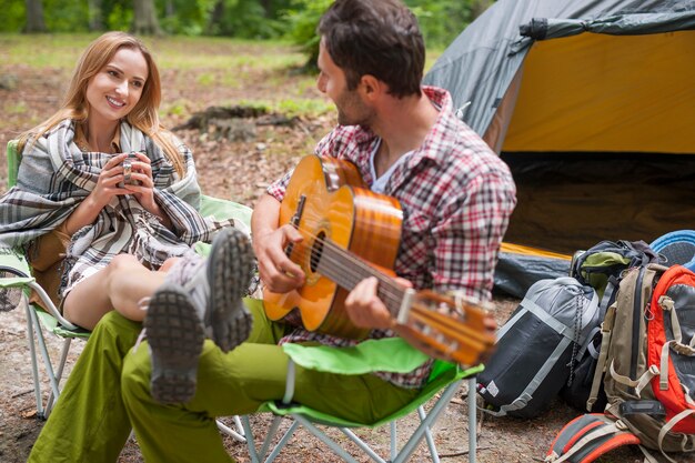 Coppia romantica in un campeggio. Uomo che suona la chitarra.