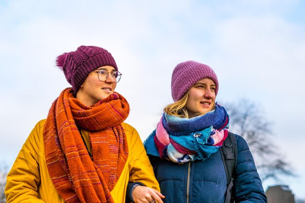 Coppia romantica lesbica in cappotti e cappelli invernali - sfondo bianco del cielo