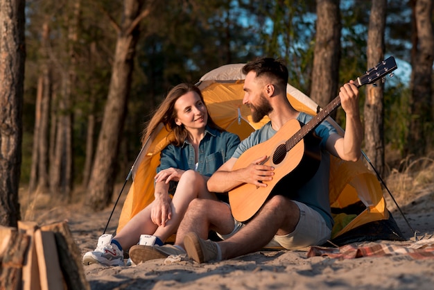 Coppia seduta accanto alla tenda e cantando