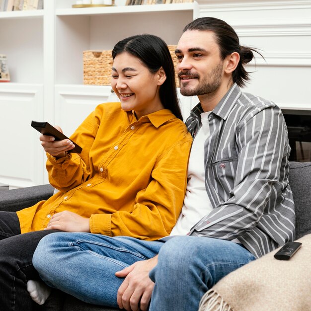 Coppia seduta sul divano a guardare la tv vista laterale