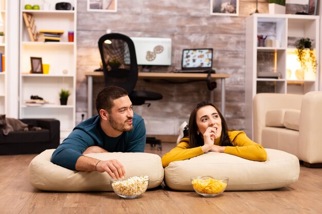 Coppia seduta sul pavimento e guardare la TV nel loro soggiorno.