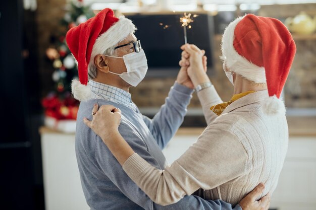 Coppia senior che balla mentre festeggia il Natale a casa durante la pandemia COVID19