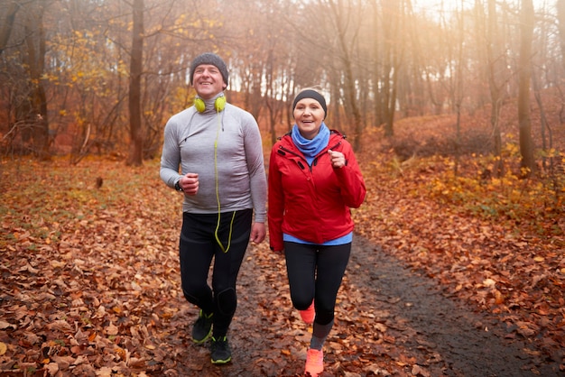 Coppia senior che fa jogging tra il sentiero nel bosco