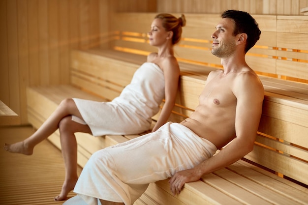 Coppia serena che si rilassa nella sauna mentre trascorre il fine settimana al centro benessere Focus è sull'uomo