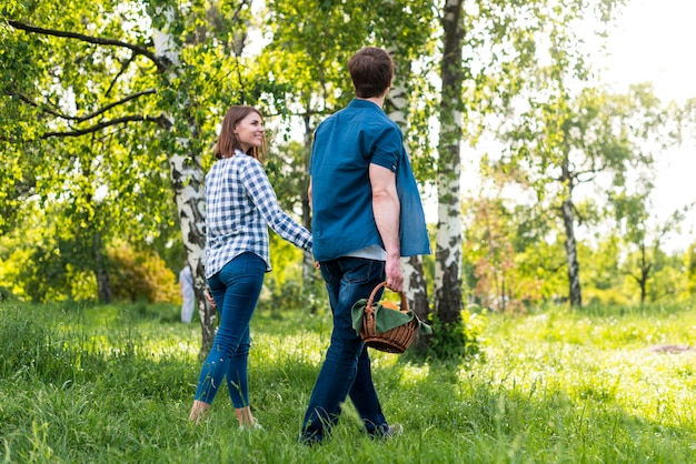 Coppia sorridendo mentre andando per picnic nella foresta