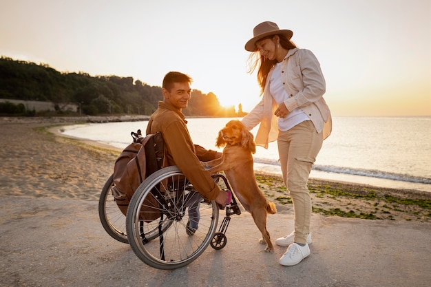 Coppia sorridente a tutto campo con cane in riva al mare