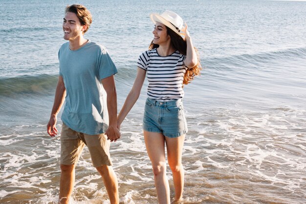 Coppia sorridente fare una passeggiata in spiaggia