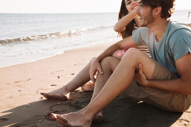 Coppia sorridente seduta accanto al mare