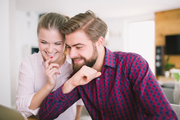 Coppia sorridente seduto al computer portatile