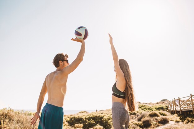 Coppia sportiva giocando a pallavolo in spiaggia