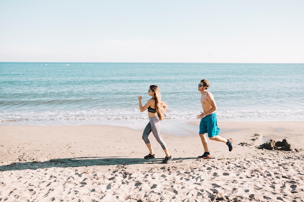 Coppia sportiva jogging in spiaggia