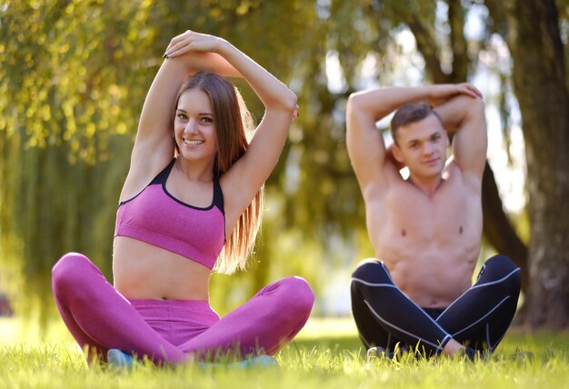 Coppia sportiva rilassante su un prato dopo esercizi di yoga nel parco autunnale.