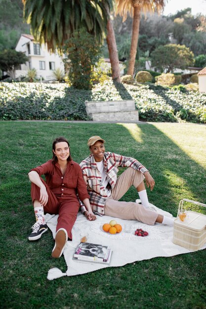 Coppia trans che si tiene per mano e sorride mentre fa un picnic al parco