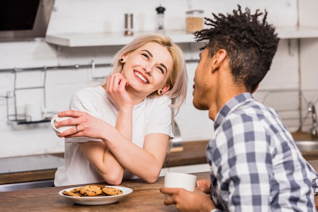 Coppie adolescenti che giudicano tazza disponente che si siede insieme facendo colazione